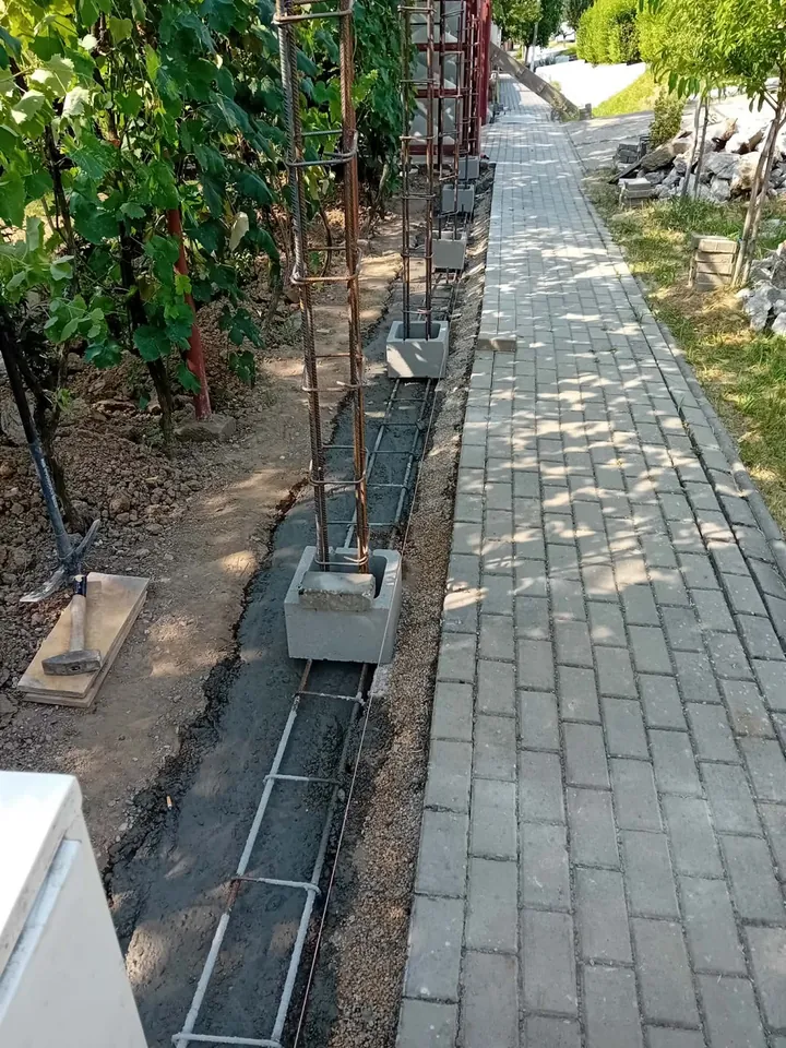Armătură liniară și carcase verticale pregătite pentru fundația și stâlpii gardului din beton